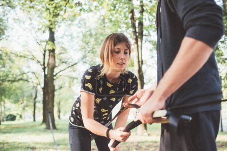 Photo for Man and woman preparing equipment fixing  the rope for slacklining training - Royalty Free Image
