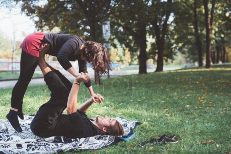 Téléchargez les photos : Deux danseurs sportifs pratiquant l'exercice acrobatique d'équilibre dans le jardin - en image libre de droit