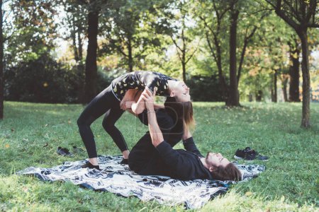 Téléchargez les photos : Athlétisme danseurs hommes et femmes pratiquant le yoga acrobatique exercice d'étirement jardin extérieur - en image libre de droit
