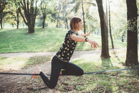 Téléchargez les photos : Sportif sportif jeune femme en plein air entraînement relâchement et acrobatique yoga marche corde raide - en image libre de droit