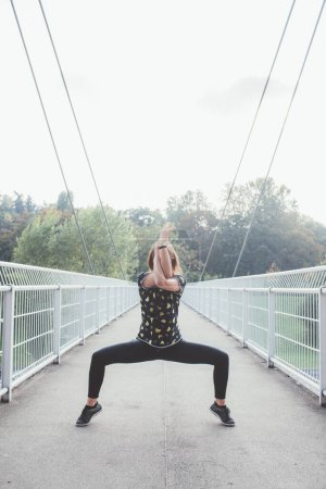 Téléchargez les photos : Jeune femme sportive dansant en plein air faisant position de yoga acrobatique effectuant entraînement - en image libre de droit