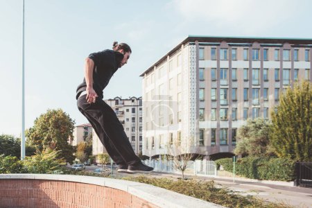 Téléchargez les photos : Sportif acrobatique homme sautant à l'extérieur exerçant tour de parkour - en image libre de droit