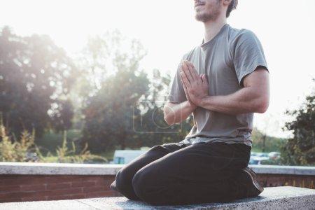 Téléchargez les photos : Cultivé homme méditant à l'extérieur faisant position de yoga méditant matin - en image libre de droit
