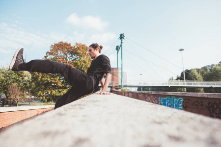 Téléchargez les photos : Acrobatique jeune homme en plein air formation parkour astuces exercices course libre - en image libre de droit