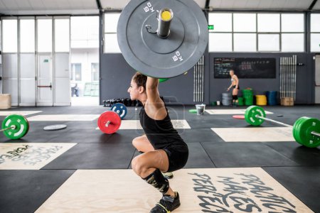 Téléchargez les photos : Athletic woman exercising deadlift in a gym using barbell power lifting - en image libre de droit