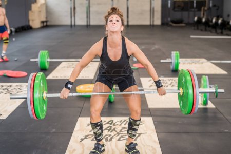 Téléchargez les photos : Young athletic fit woman training indoors gym weight lifting using barbells concentrating on effort - en image libre de droit