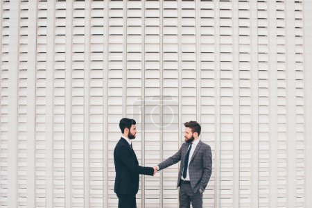 Téléchargez les photos : Jeune homme d'affaires professionnel barbu serrant la main avec un partenaire pour célébrer partenariat et affaire - en image libre de droit