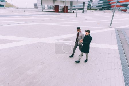 Téléchargez les photos : Deux jeunes hommes d'affaires tablette marche en plein air - en image libre de droit
