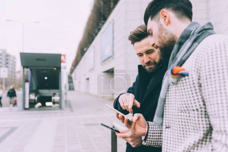Téléchargez les photos : Deux jeunes barbus, hommes d'affaires en plein air en utilisant un téléphone intelligent - en image libre de droit