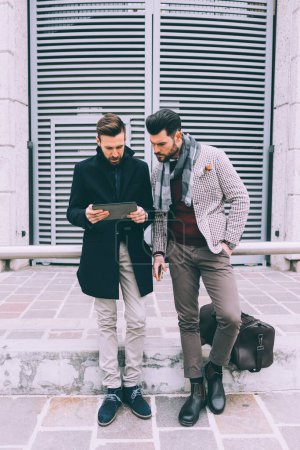 Photo for Two young bearded business men outdoor using tablet - Royalty Free Image