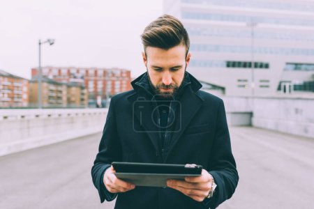 Téléchargez les photos : Jeune homme barbu affaires en plein air en utilisant la tablette - en image libre de droit