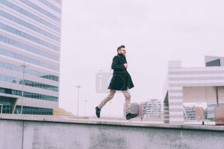 Téléchargez les photos : Jeune homme d'affaires barbu courir en plein air - en image libre de droit