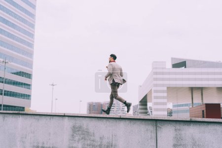Téléchargez les photos : Jeune homme d'affaires barbu courir en plein air - en image libre de droit