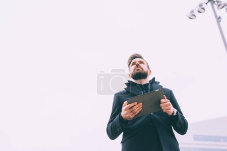 Téléchargez les photos : Jeune homme barbu affaires en plein air en utilisant la tablette - en image libre de droit