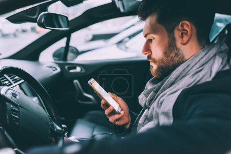 Téléchargez les photos : Jeune homme d'affaires barbu assis voiture téléphone intelligent - en image libre de droit