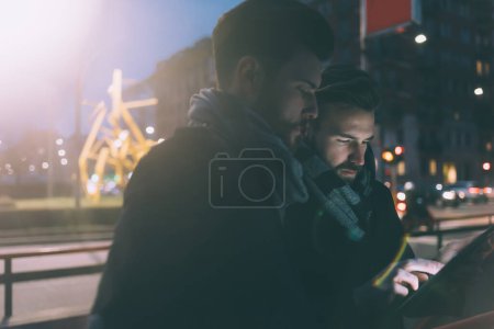 Téléchargez les photos : Deux jeunes hommes d'affaires en plein air utilisant la tablette - en image libre de droit