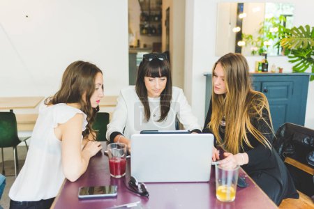 Téléchargez les photos : Trois femmes d'affaires multitâche en utilisant tablette et ordinateur - en image libre de droit
