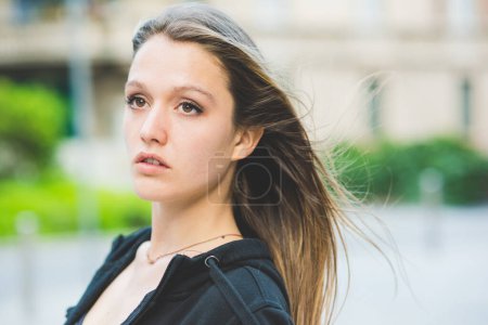 Photo for Portrait of a young beautiful millennial woman outdoor in the city, overlooking pensive - airy, serious, thoughtful concept - Royalty Free Image