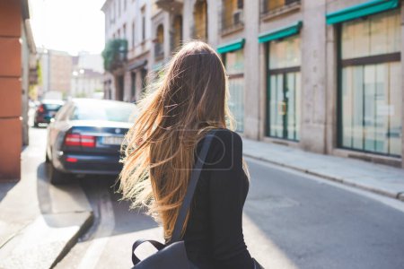 Téléchargez les photos : Vue arrière des jeunes milléniaux femme marchant en plein air dans la ville - en image libre de droit