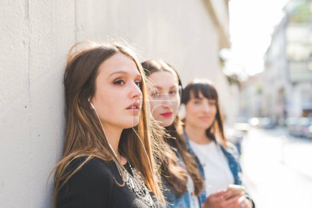 Photo for Three beautiful young women millennials listening music - Royalty Free Image