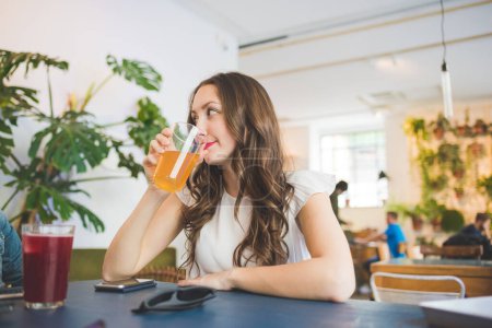 Photo for Young woman sitting indoors bar drinking soft drink - Royalty Free Image