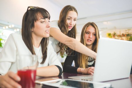 Photo for Three young beautiful caucasian millennials women indoor using computer discussing - Royalty Free Image