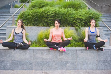 Téléchargez les photos : Trois jeunes femmes sportives faisant du yoga en plein air - en image libre de droit