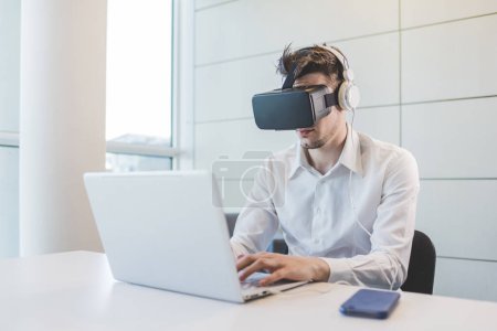 Foto de Joven hombre de negocios caucásico utilizando visor 3D y PC - Imagen libre de derechos