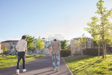 Foto de Dos amigos multiétnicos caminando juntos al aire libre - Imagen libre de derechos