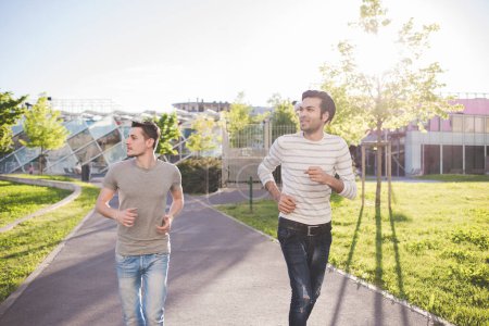 Foto de Dos amigos multiétnicos corriendo juntos al aire libre - Imagen libre de derechos