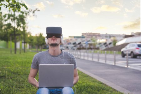 Foto de Joven hombre caucásico utilizando visor 3D y juegos de PC al aire libre - Imagen libre de derechos
