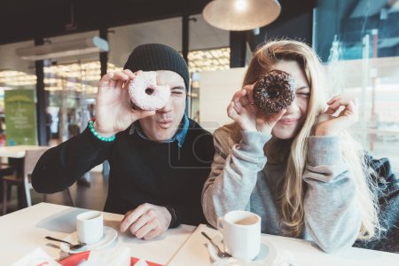 Photo for Two beautiful friends playing  with donuts - Royalty Free Image