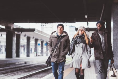 Foto de Tres jóvenes amigos multiétnicos que se divierten paseando por la estación de tren - Imagen libre de derechos
