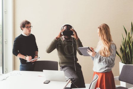 Foto de Tres compañeros de trabajo jóvenes que trabajan en interiores utilizando gafas 3d tecnología wereable, concepto de negocio creativo - Imagen libre de derechos