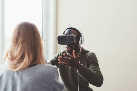 Téléchargez les photos : Homme noir intérieur utilisant visionneuse 3D - jeu vidéo, réalité augmentée, concept de technologie lisible - en image libre de droit