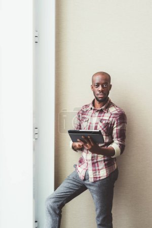 Foto de Joven hombre de negocios negro posando en interiores usando tableta - Imagen libre de derechos