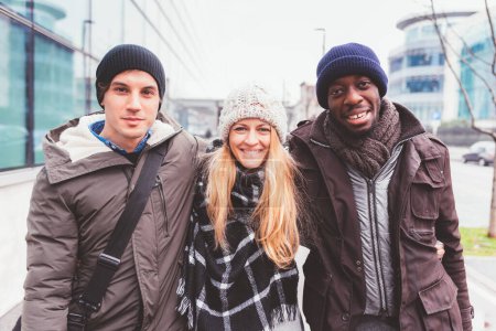 Téléchargez les photos : Trois jeunes amis marchant ensemble dans la rue. amitié, jour de congé, joyeuse - en image libre de droit
