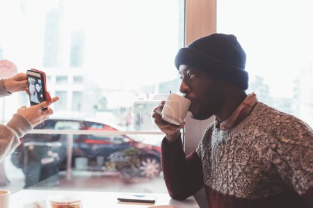 Téléchargez les photos : Jeune homme noir adulte assis dans le café bar à boire - en image libre de droit