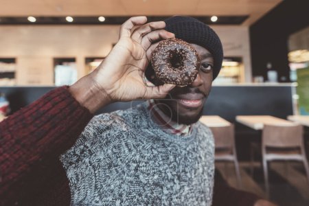 Photo for Young beautiful black man indoor bar playing donuts - playful, childhood, hungry concept - Royalty Free Image