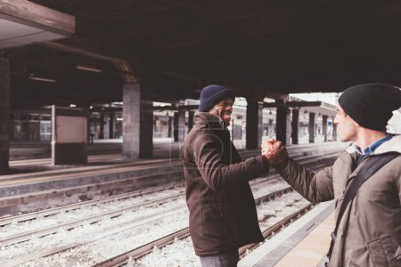 Foto de Dos hombres multiétnicos freinds estrechando las manos sonriendo - Imagen libre de derechos