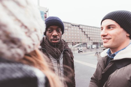 Téléchargez les photos : Trois jeunes amis bavardant ensemble dans la rue - en image libre de droit