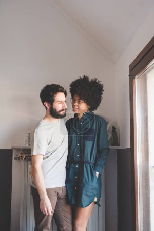 Téléchargez les photos : Jeune couple multiethnique câlin souriant intérieur - en image libre de droit