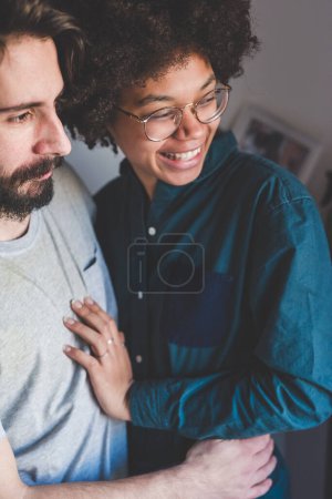 Téléchargez les photos : Jeune couple multiethnique embrassant souriant ensemble à la maison - en image libre de droit