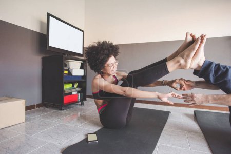 Foto de Pareja multiétnica en casa practicando deporte haciendo fitness yoga - Imagen libre de derechos