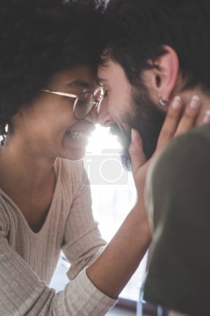 Photo for Young multiethnic couple hugging smiling together at home - Royalty Free Image