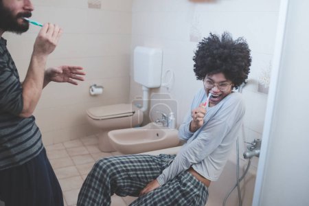 Photo for Young multiethnic couple indoor bathroom brushing teeth - Royalty Free Image