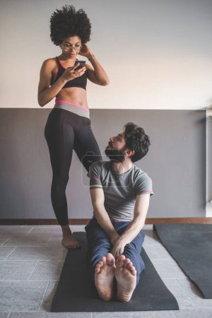 Foto de Pareja multiétnica en casa practicando deporte haciendo yoga fitness clase online smartphone - Imagen libre de derechos