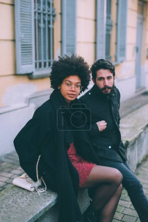 Téléchargez les photos : Jeune couple multiethnique posant à l'extérieur des rues de la ville au coucher du soleil - en image libre de droit