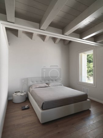 Foto de Interior del dormitorio moderno en el ático en el primer plano de la cama, mientras que el suelo y el techo están hechos de madera - Imagen libre de derechos