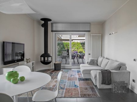 Foto de Modern living room interior with iron fireplace, fabric sofa and carpet overlooking on the terrace - Imagen libre de derechos